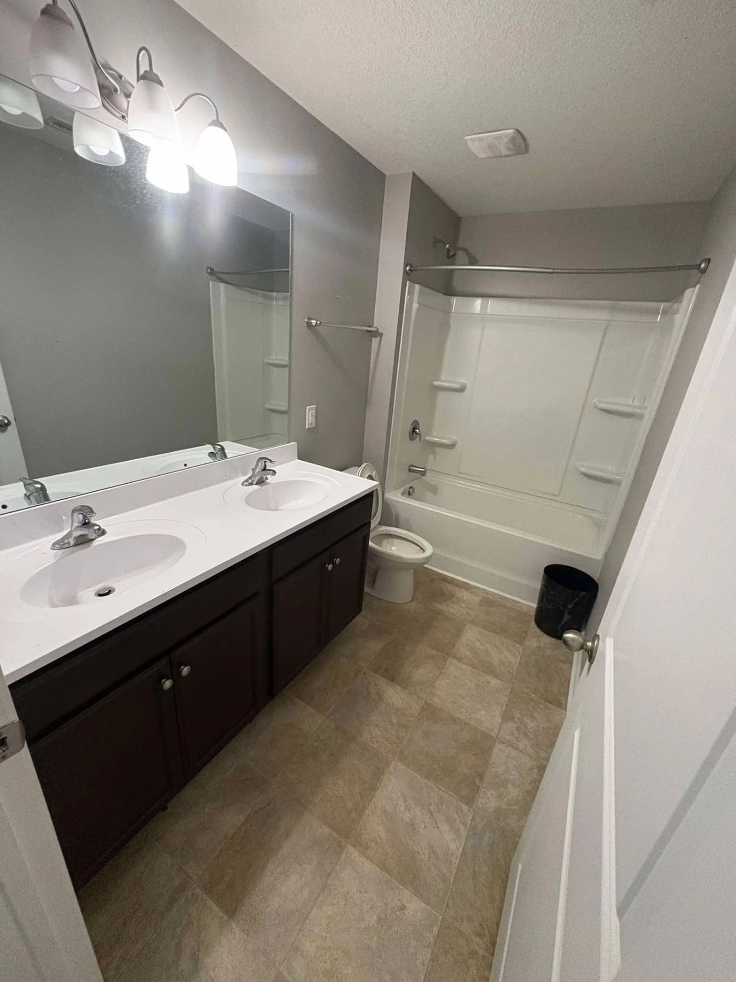 After cleaning: the same guest bathroom with clear white counters, polished mirror, clean tub and swept tile floor