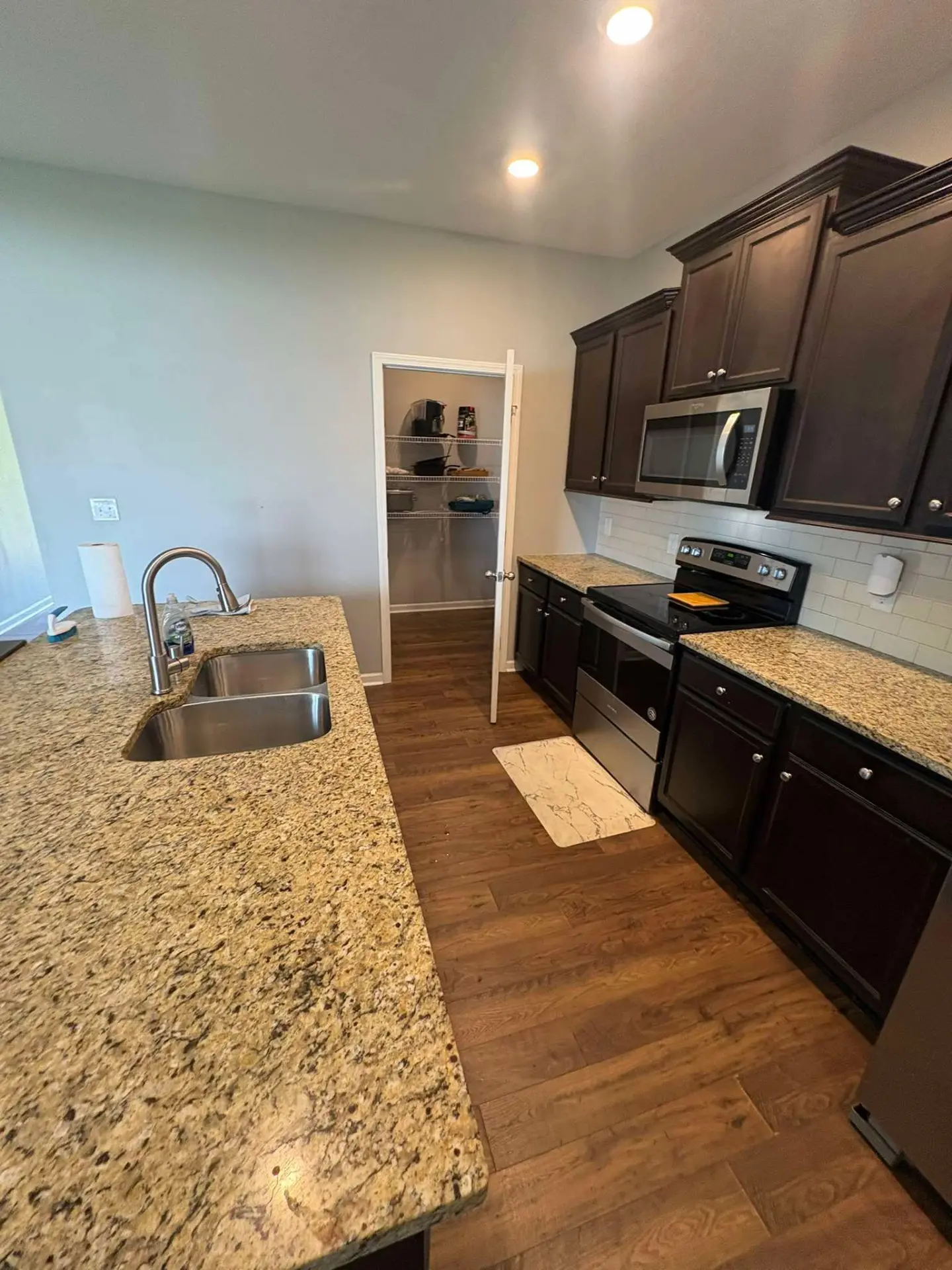 After cleaning: the same kitchen with clear granite counters, a shining sink and clean appliances